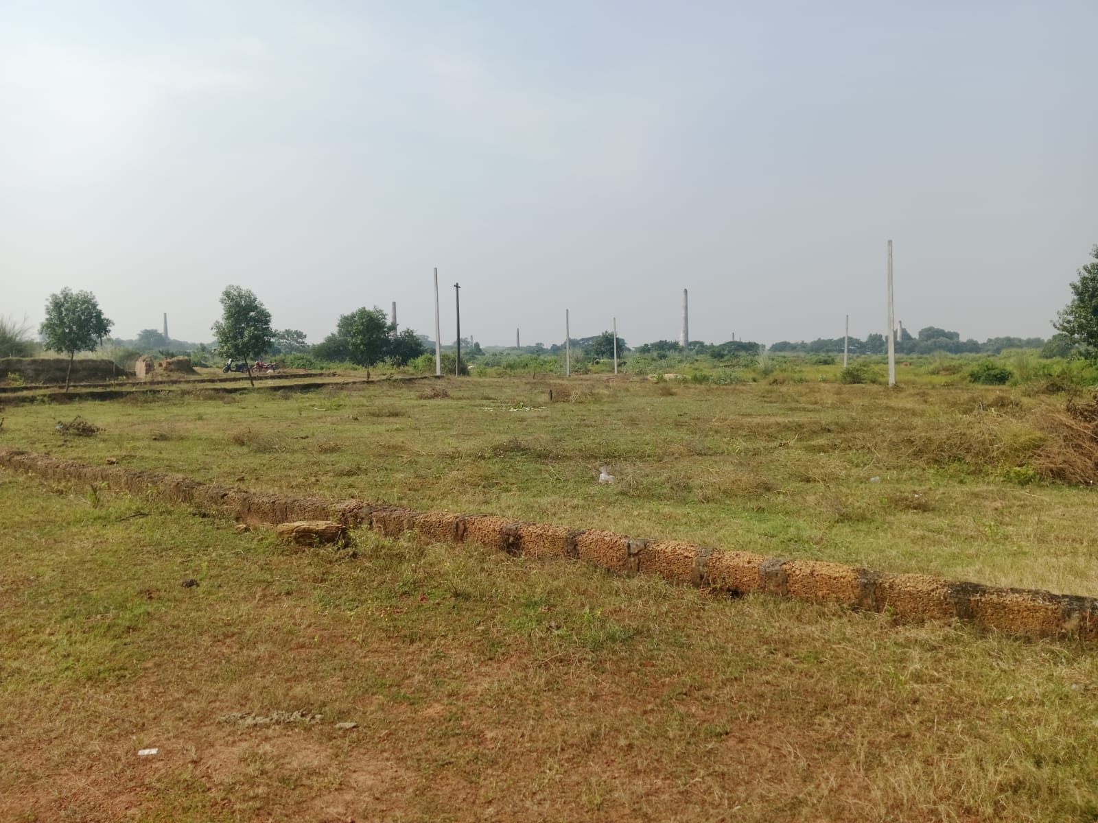 Panoramic view of Mohan Dham demarcated plots with electric poles and brick-kiln horizon